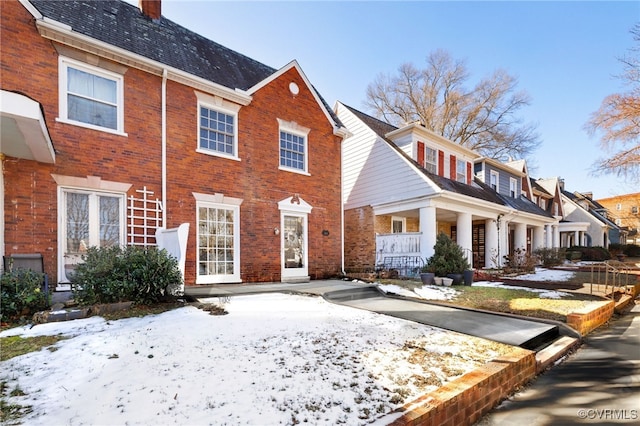 view of front of home with a chimney and brick siding