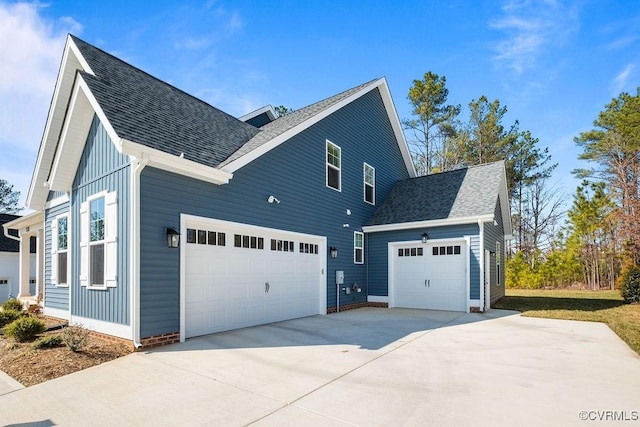 view of home's exterior with an attached garage, a shingled roof, board and batten siding, and concrete driveway