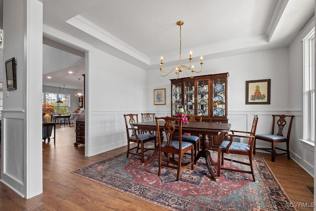 dining space featuring a raised ceiling, a notable chandelier, and wood finished floors