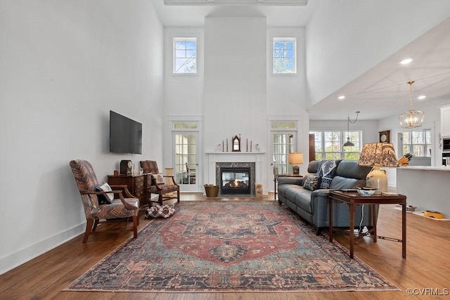 living room with a high end fireplace, plenty of natural light, baseboards, and wood finished floors