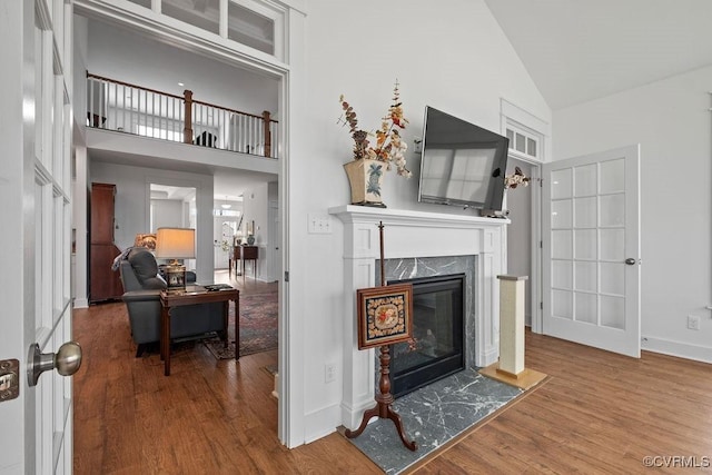 living area featuring high vaulted ceiling, a high end fireplace, and wood finished floors