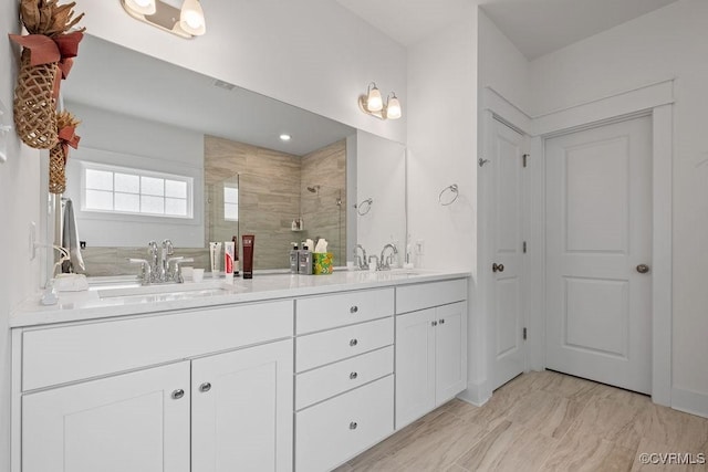 full bathroom featuring double vanity, a sink, and a shower stall