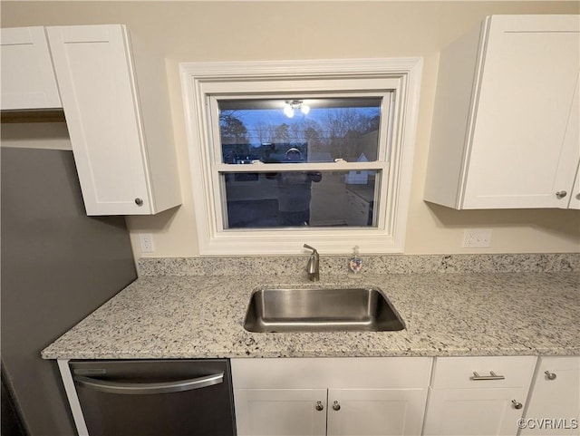 kitchen with light stone counters, stainless steel dishwasher, sink, and white cabinets