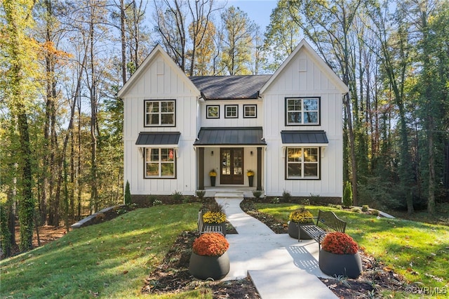 modern farmhouse style home featuring a standing seam roof, a front lawn, board and batten siding, and roof with shingles