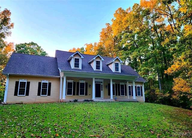 cape cod house featuring a front lawn, roof with shingles, and a porch