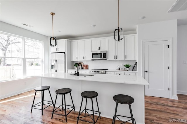 kitchen with pendant lighting, sink, an island with sink, and appliances with stainless steel finishes