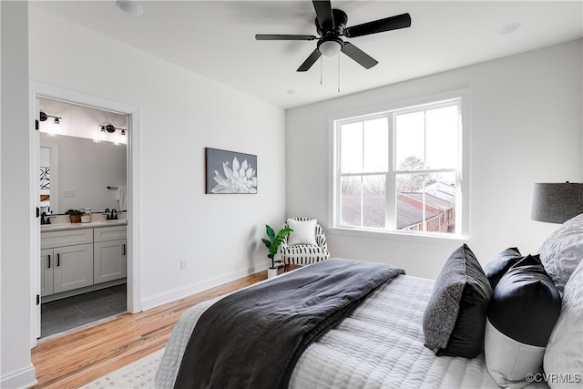 bedroom with connected bathroom, light hardwood / wood-style floors, sink, and ceiling fan