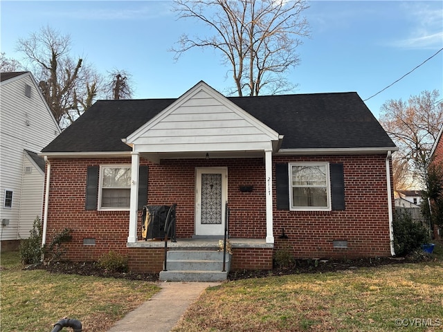 bungalow-style home with roof with shingles, brick siding, crawl space, and a front yard