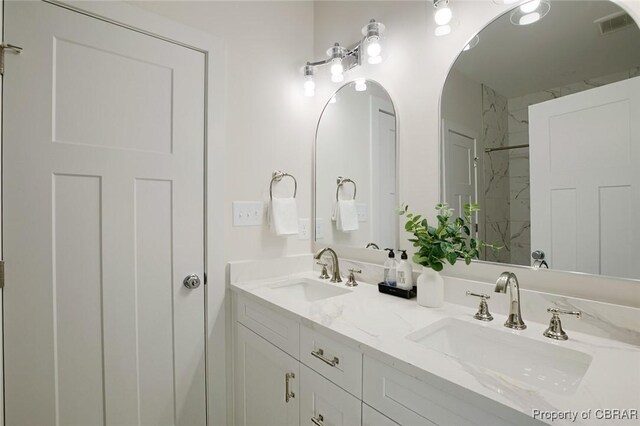 bathroom featuring tiled shower and vanity