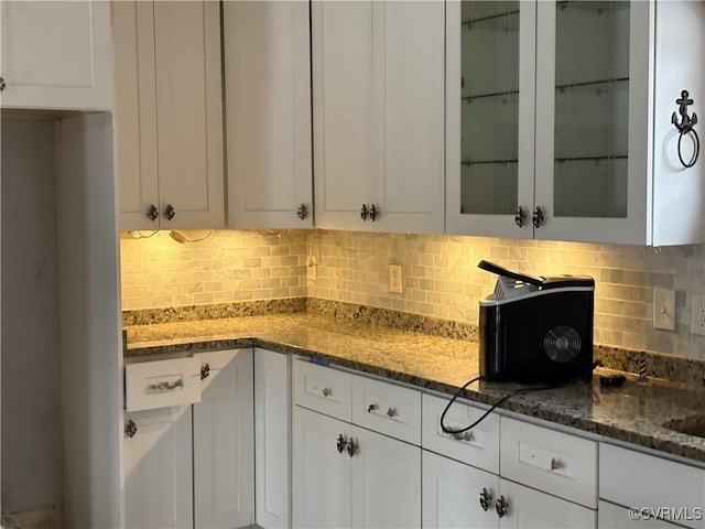 kitchen with dark stone countertops, white cabinets, and decorative backsplash