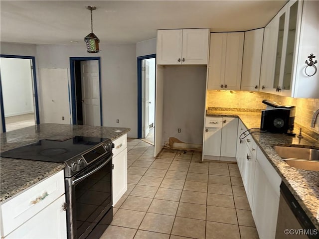 kitchen featuring light tile patterned flooring, sink, dark stone countertops, range with electric stovetop, and white cabinets