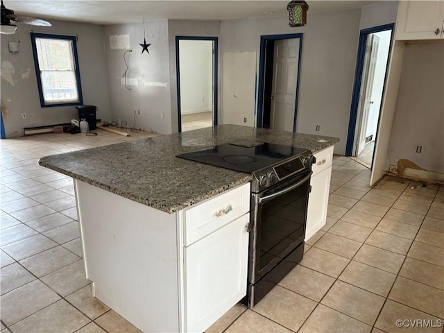 kitchen featuring range with electric stovetop, dark stone countertops, white cabinets, and light tile patterned floors