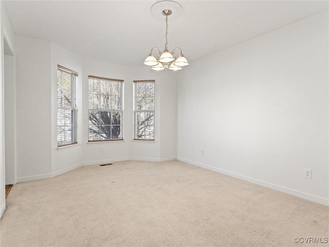 carpeted empty room featuring an inviting chandelier