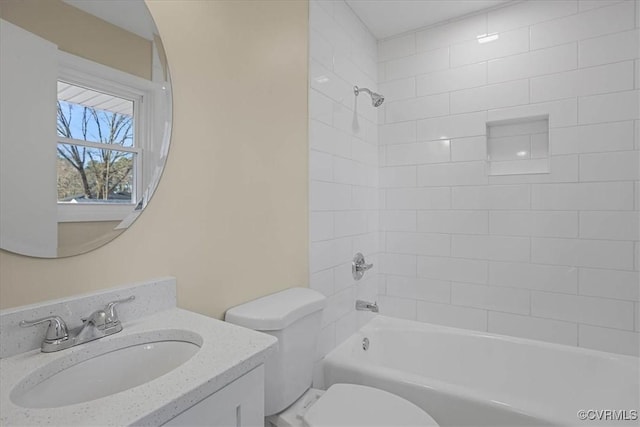 full bathroom featuring vanity, tiled shower / bath, and toilet