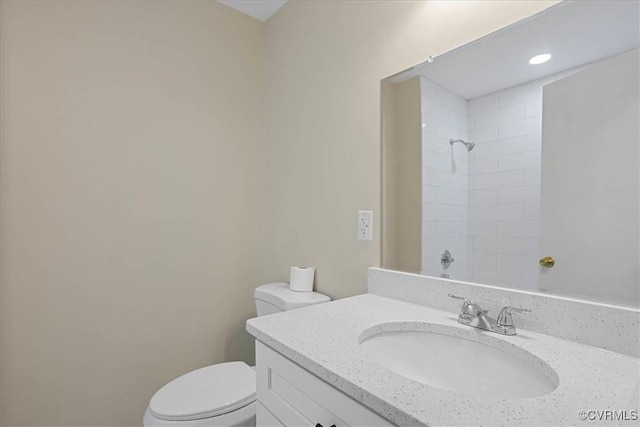 bathroom featuring vanity, tiled shower, and toilet