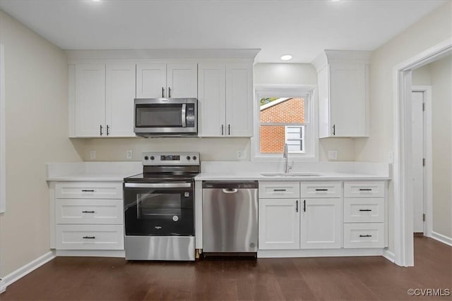 kitchen with appliances with stainless steel finishes, sink, white cabinets, and dark hardwood / wood-style floors