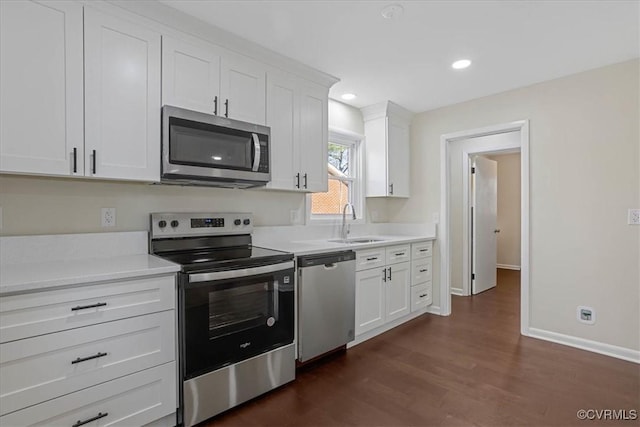 kitchen with stainless steel appliances, sink, dark wood-type flooring, and white cabinets