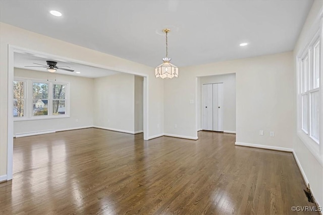 unfurnished room with dark wood-type flooring, ceiling fan, and baseboard heating