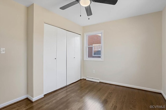 unfurnished bedroom featuring a baseboard heating unit, a closet, dark hardwood / wood-style floors, and ceiling fan