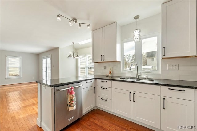 kitchen featuring white cabinetry, dishwasher, sink, and hanging light fixtures