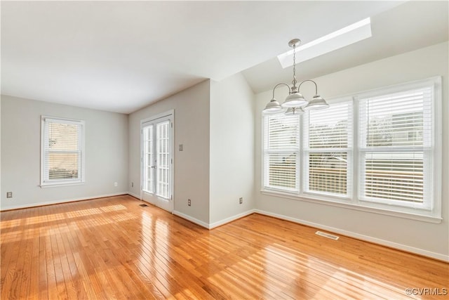 unfurnished dining area with hardwood / wood-style flooring, lofted ceiling, and a notable chandelier