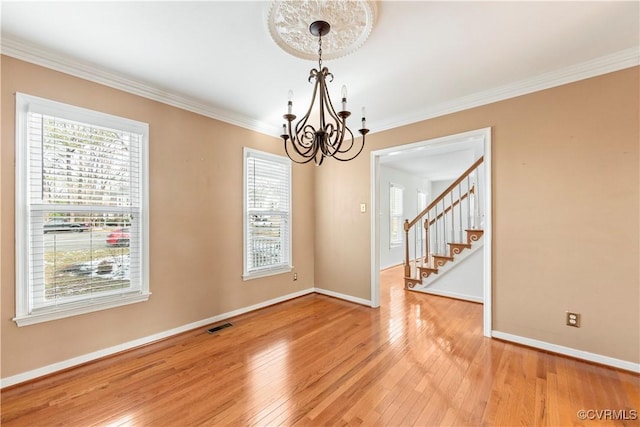 unfurnished room with ornamental molding, plenty of natural light, wood-type flooring, and a notable chandelier