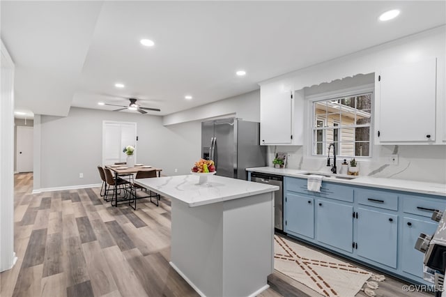 kitchen with a kitchen island, appliances with stainless steel finishes, white cabinetry, sink, and blue cabinetry