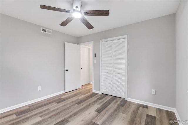 unfurnished bedroom featuring ceiling fan, a closet, and light wood-type flooring