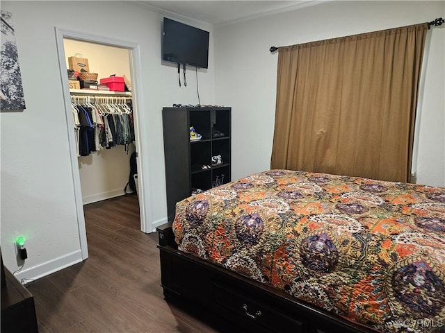 bedroom featuring dark wood finished floors, a spacious closet, a closet, crown molding, and baseboards