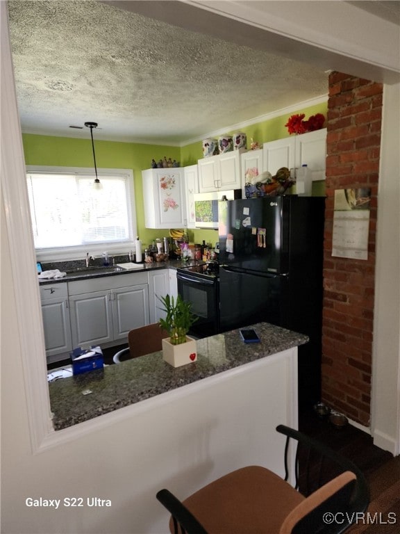 kitchen featuring a sink, a textured ceiling, white cabinetry, and black appliances