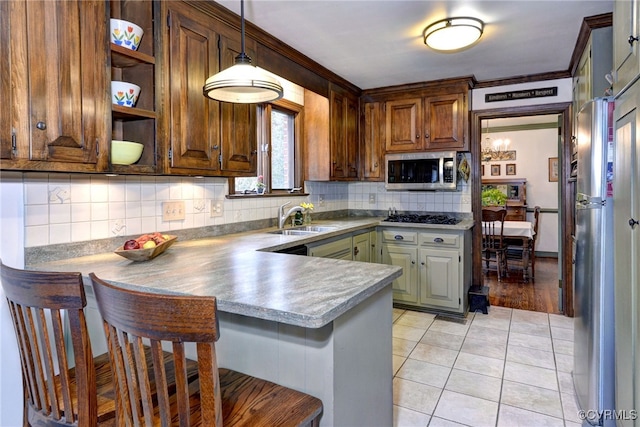 kitchen with a breakfast bar area, stainless steel appliances, a peninsula, decorative backsplash, and decorative light fixtures