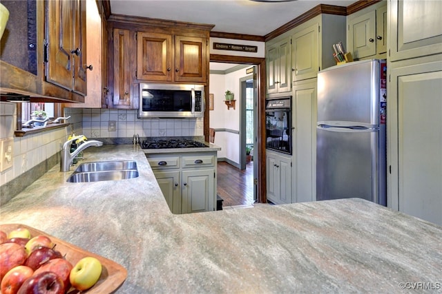 kitchen featuring decorative backsplash, appliances with stainless steel finishes, light countertops, crown molding, and a sink