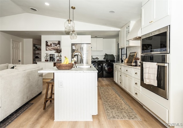 kitchen with decorative light fixtures, white cabinetry, sink, a kitchen island with sink, and washer and clothes dryer