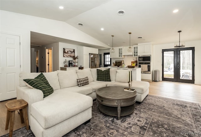 living room with hardwood / wood-style flooring, vaulted ceiling, and a wealth of natural light