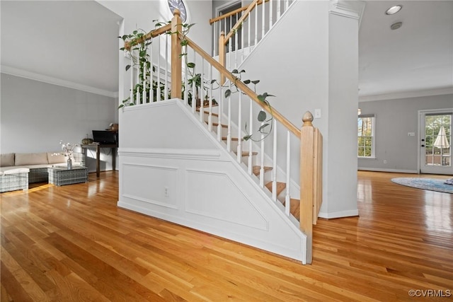 stairs with hardwood / wood-style floors, crown molding, and a towering ceiling