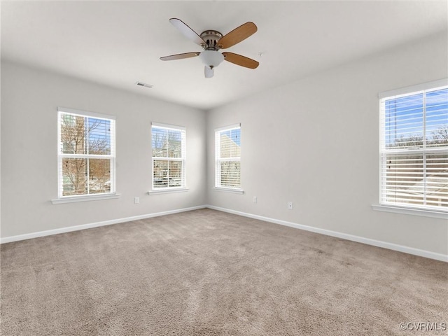 carpeted spare room with visible vents, baseboards, and a ceiling fan
