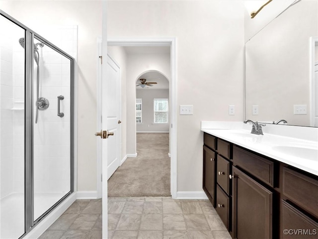 bathroom featuring a shower stall, a ceiling fan, double vanity, and a sink