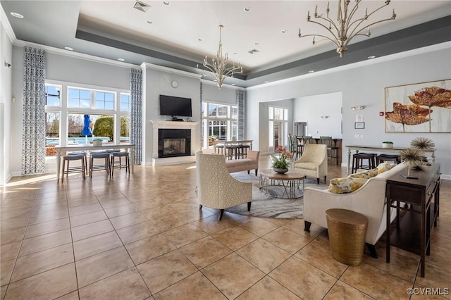 living room with light tile patterned flooring, a towering ceiling, a chandelier, a tray ceiling, and crown molding