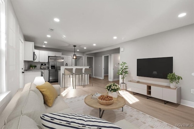 living area with light wood-type flooring, baseboards, visible vents, and recessed lighting