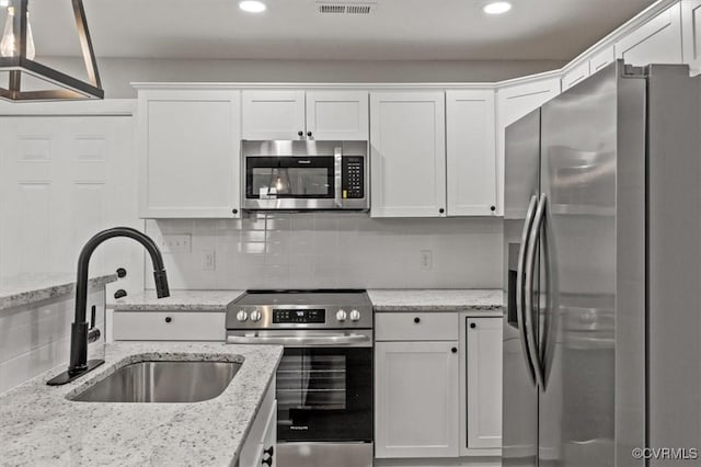 kitchen featuring white cabinetry, decorative backsplash, stainless steel appliances, and a sink