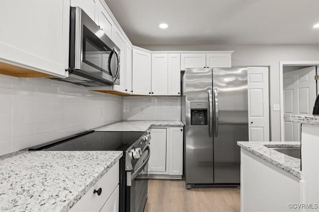 kitchen featuring recessed lighting, light wood-style flooring, decorative backsplash, appliances with stainless steel finishes, and white cabinetry