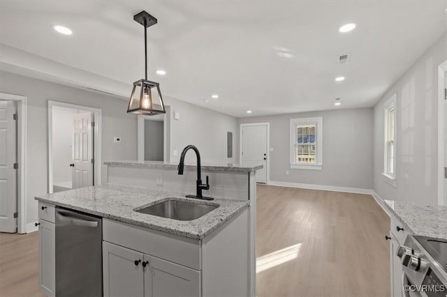 kitchen featuring light wood-style flooring, stainless steel appliances, a sink, visible vents, and open floor plan