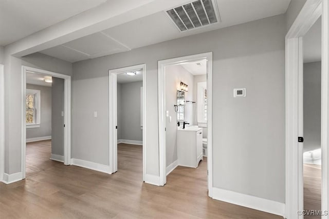 interior space featuring baseboards, visible vents, a sink, and light wood finished floors