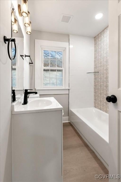 full bath featuring visible vents, vanity, and wood finished floors