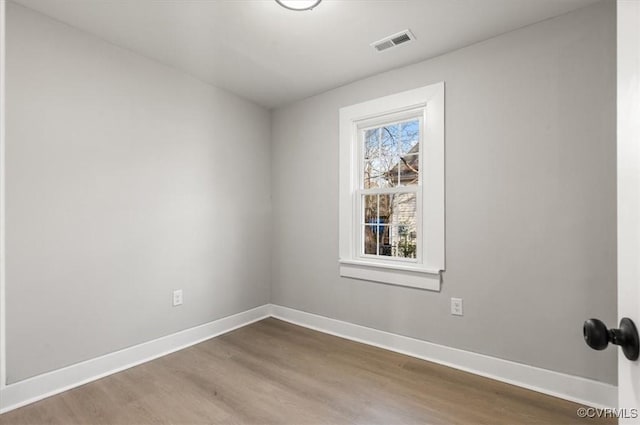 empty room with baseboards, visible vents, and wood finished floors