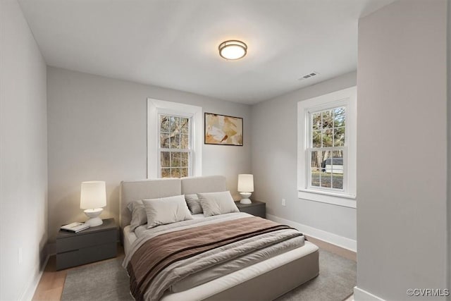 bedroom with wood finished floors, visible vents, and baseboards