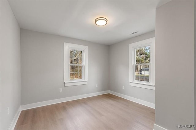 empty room featuring visible vents, baseboards, and wood finished floors