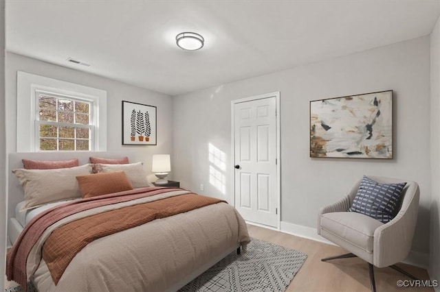 bedroom featuring visible vents, baseboards, and wood finished floors