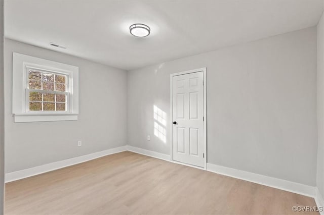 empty room featuring baseboards, visible vents, and light wood finished floors