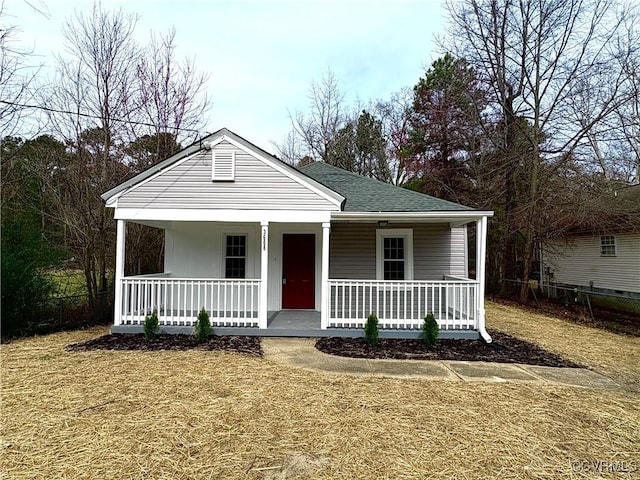 view of front of house featuring a shingled roof, covered porch, and fence